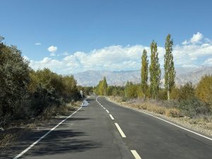 A picturesque road in a mountainous landscape with fall foliage and clear blue skies.